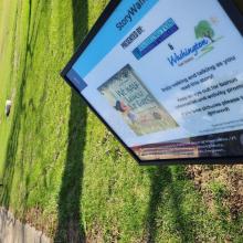 Outdoor sign telling readers to enjoy story walk. 