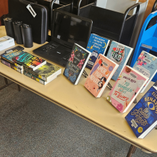 Laptop and books and tech gear on table. 