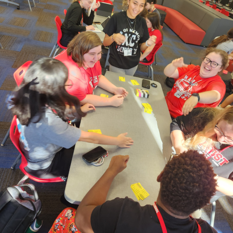 A group of students play a game around a table. 