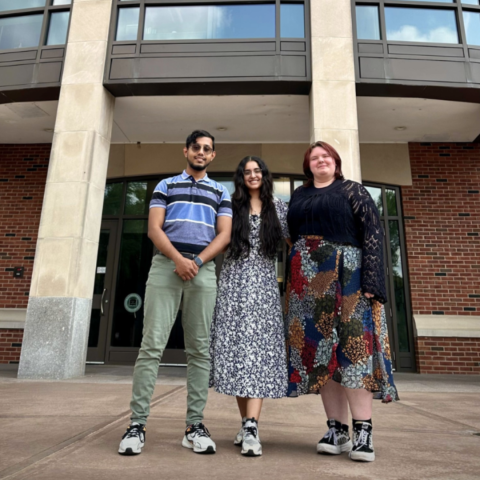 Three people standing in front of library.