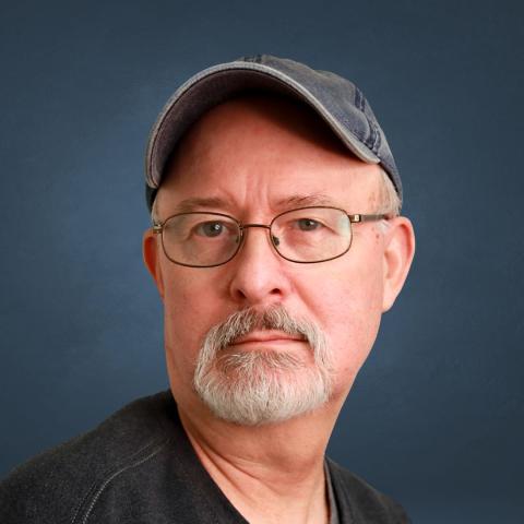 Alan Schnelle headshot with a dark blue background